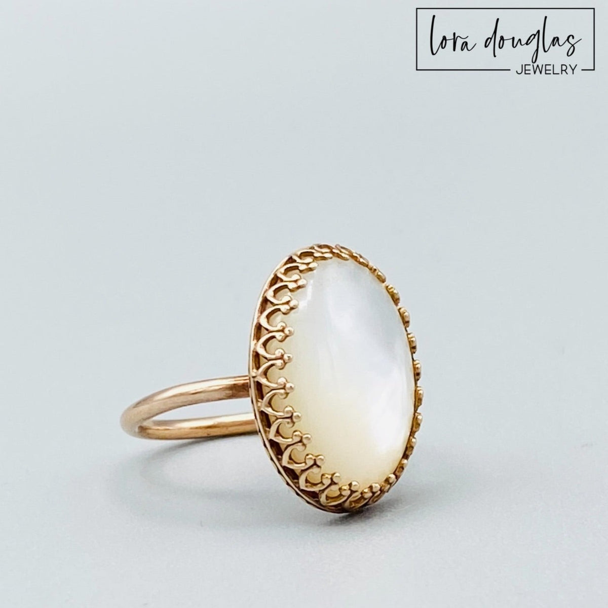 Mother of Pearl ring featuring an 18 x 13 mm natural shell stone in a warm bronze setting. This size 6 artisan ring showcases the luminous iridescence of Mother of Pearl and makes a distinctive jewelry gift for her.