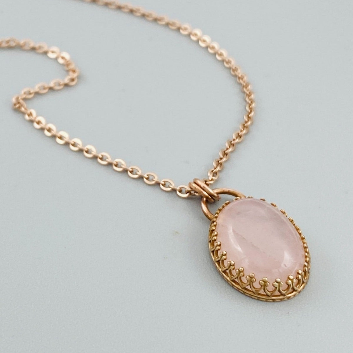 Natural rose quartz necklace featuring a soft pink gemstone in a bronze pendant setting, paired with an 18 inch stainless steel chain for shoppers looking for simple natural stone jewelry.
