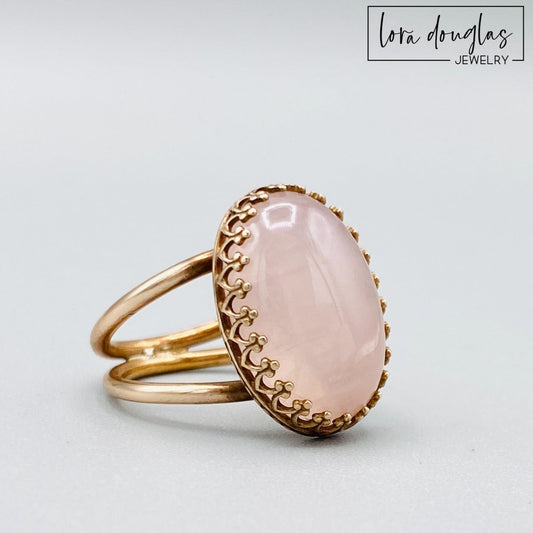 Natural rose quartz ring featuring an 18mm x 13mm soft pink gemstone set in warm bronze, shown as a finished US size 6 statement ring for shoppers looking for meaningful natural stone jewelry.
