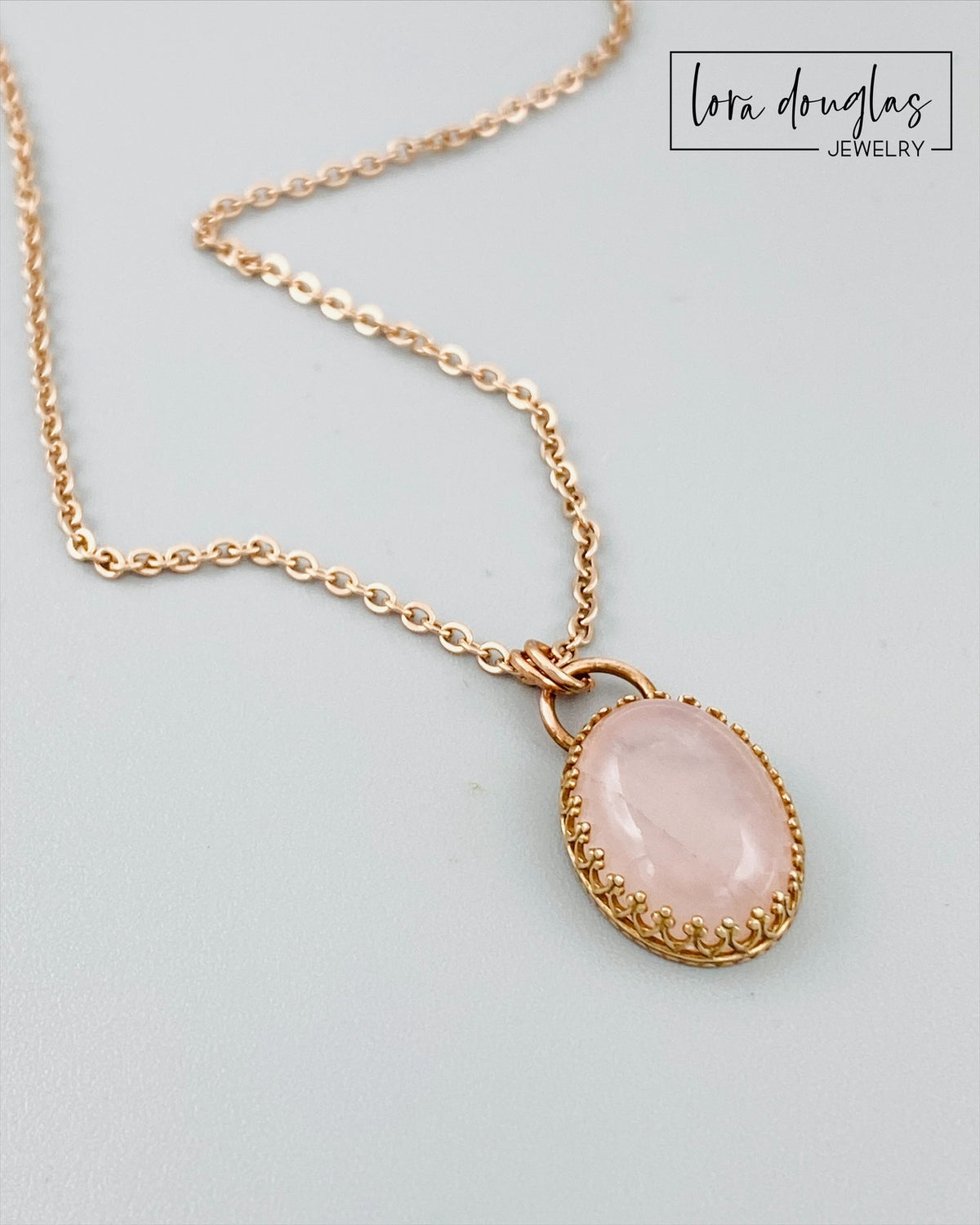 Natural stone pendant necklace featuring rose quartz with soft pink coloring, a bronze setting and stainless steel chain, designed for shoppers seeking understated gemstone jewelry with romantic symbolism.
