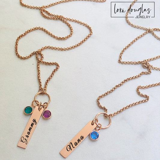 Rose gold necklaces with name charms and gemstones on a light background, featuring Lora Douglas Jewelry branding.