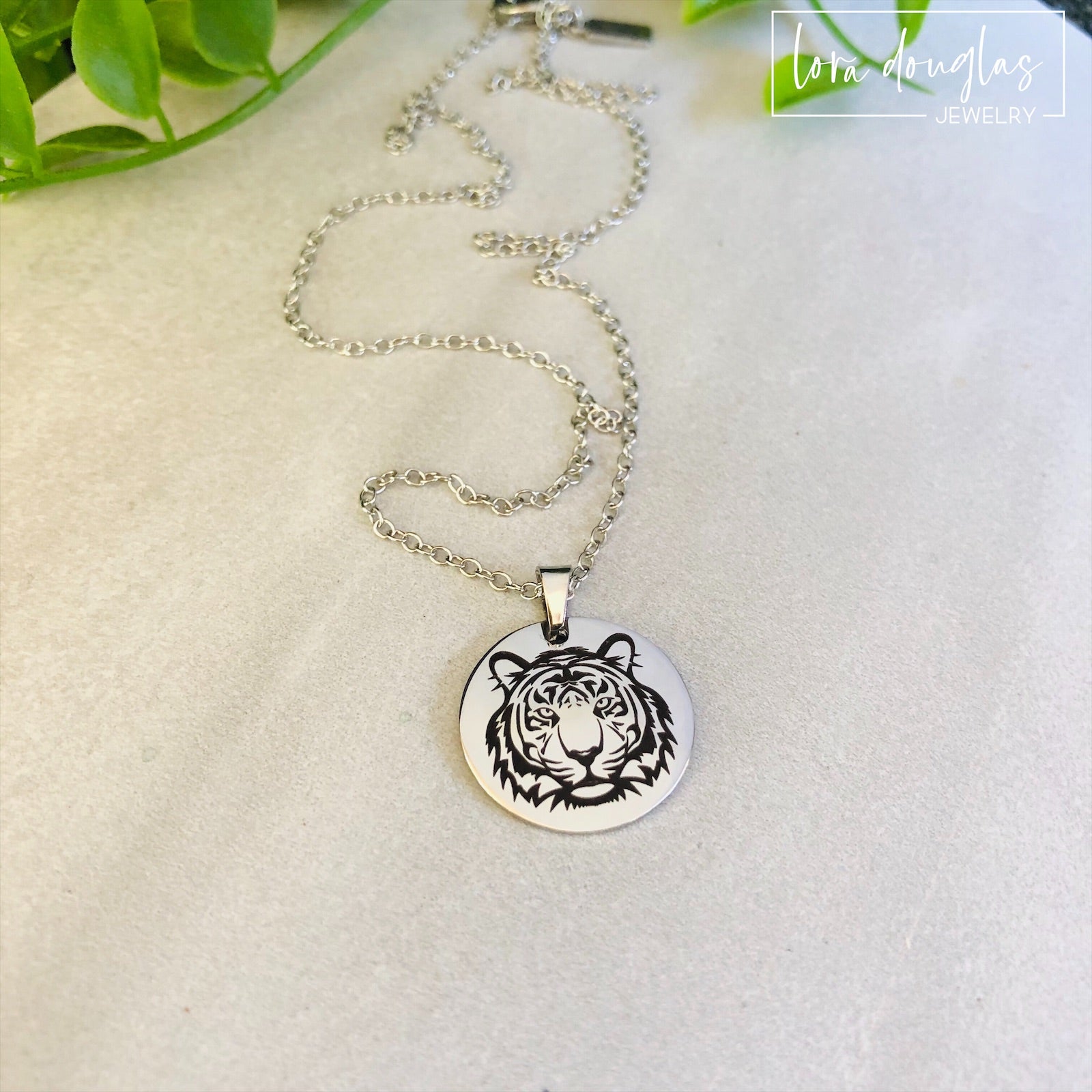 Two pieces of jewelry, a necklace and a bracelet, featuring round pendants with a black and white tiger design on a silver-colored background.