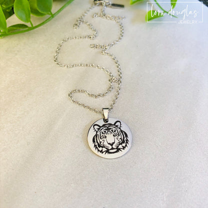 Two pieces of jewelry, a necklace and a bracelet, featuring round pendants with a black and white tiger design on a silver-colored background.