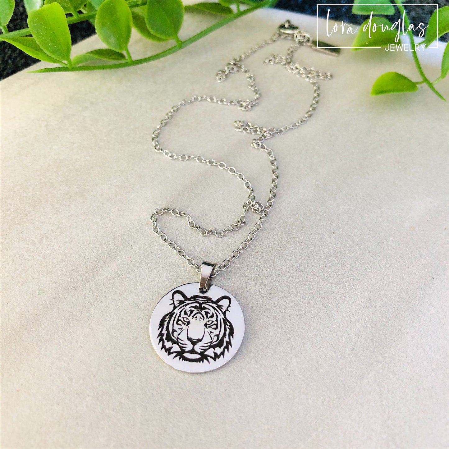 Two pieces of jewelry, a necklace and a bracelet, featuring round pendants with a black and white tiger design on a silver-colored background.