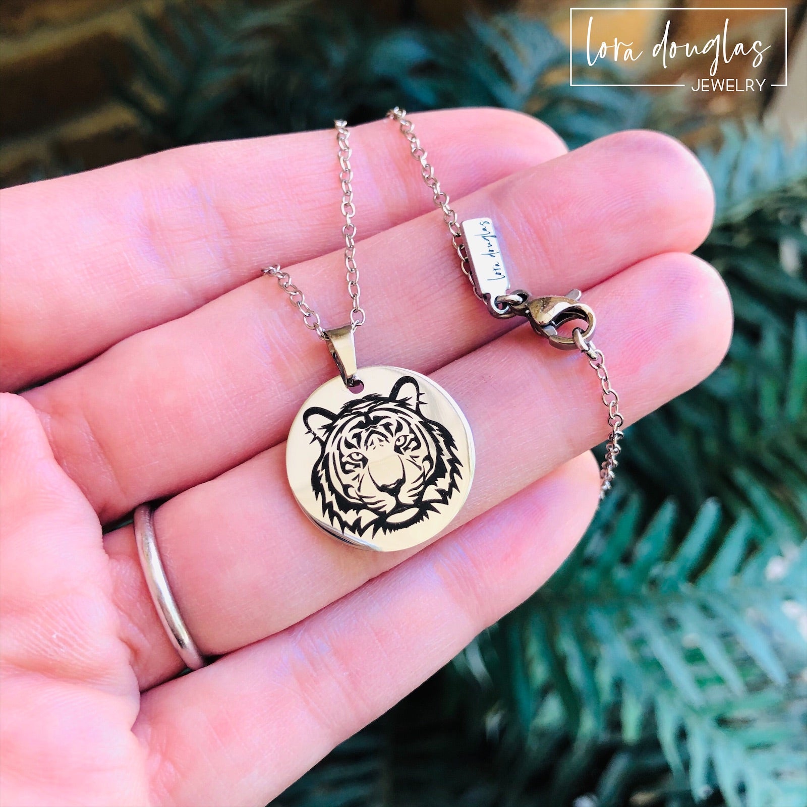 a necklace and a bracelet, featuring round pendants with a black and white tiger design on a silver-colored background.