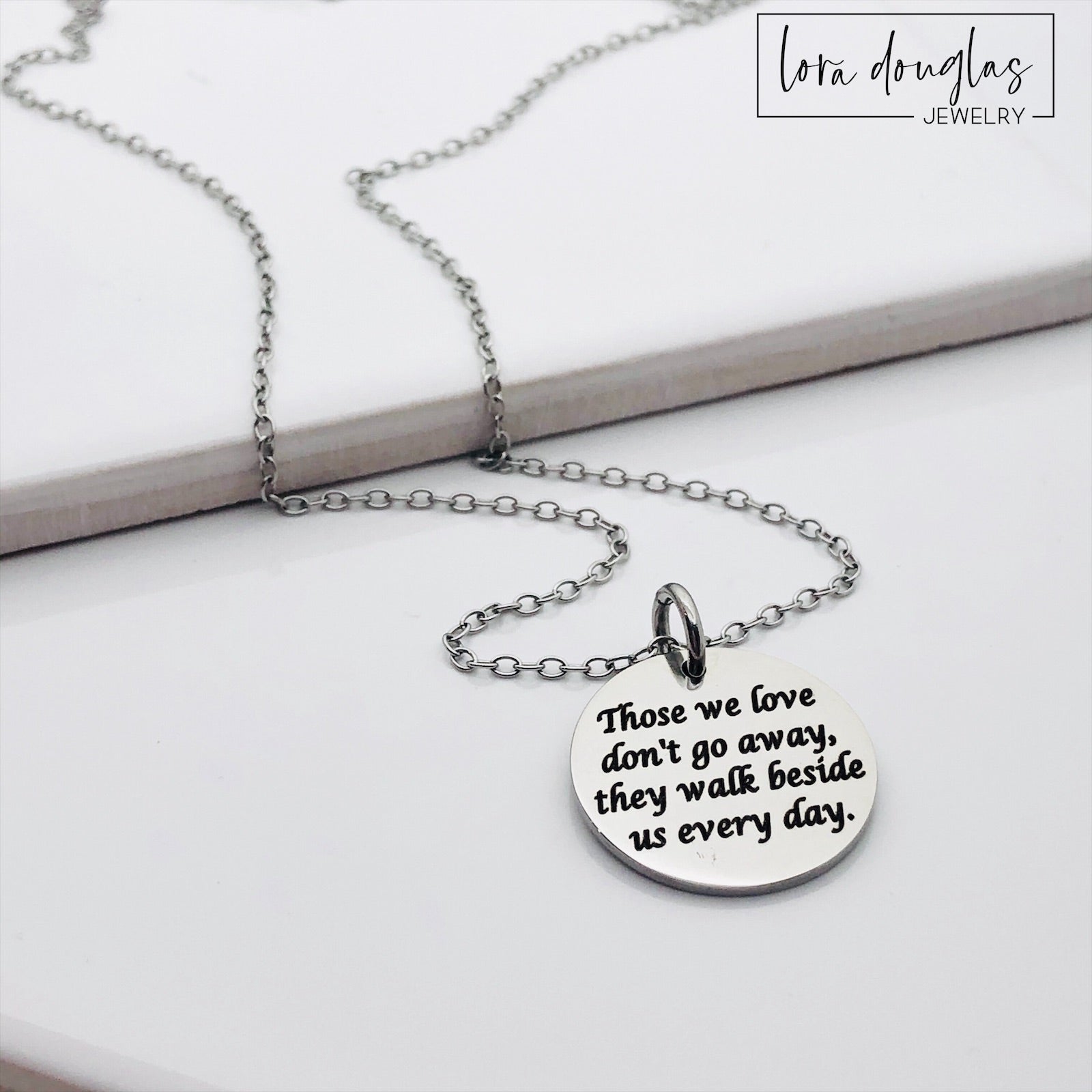 Silver necklace with a round pendant on a white background. Engraved with Those We Love Don't Go Away They Walk Beside Us Every Day.
