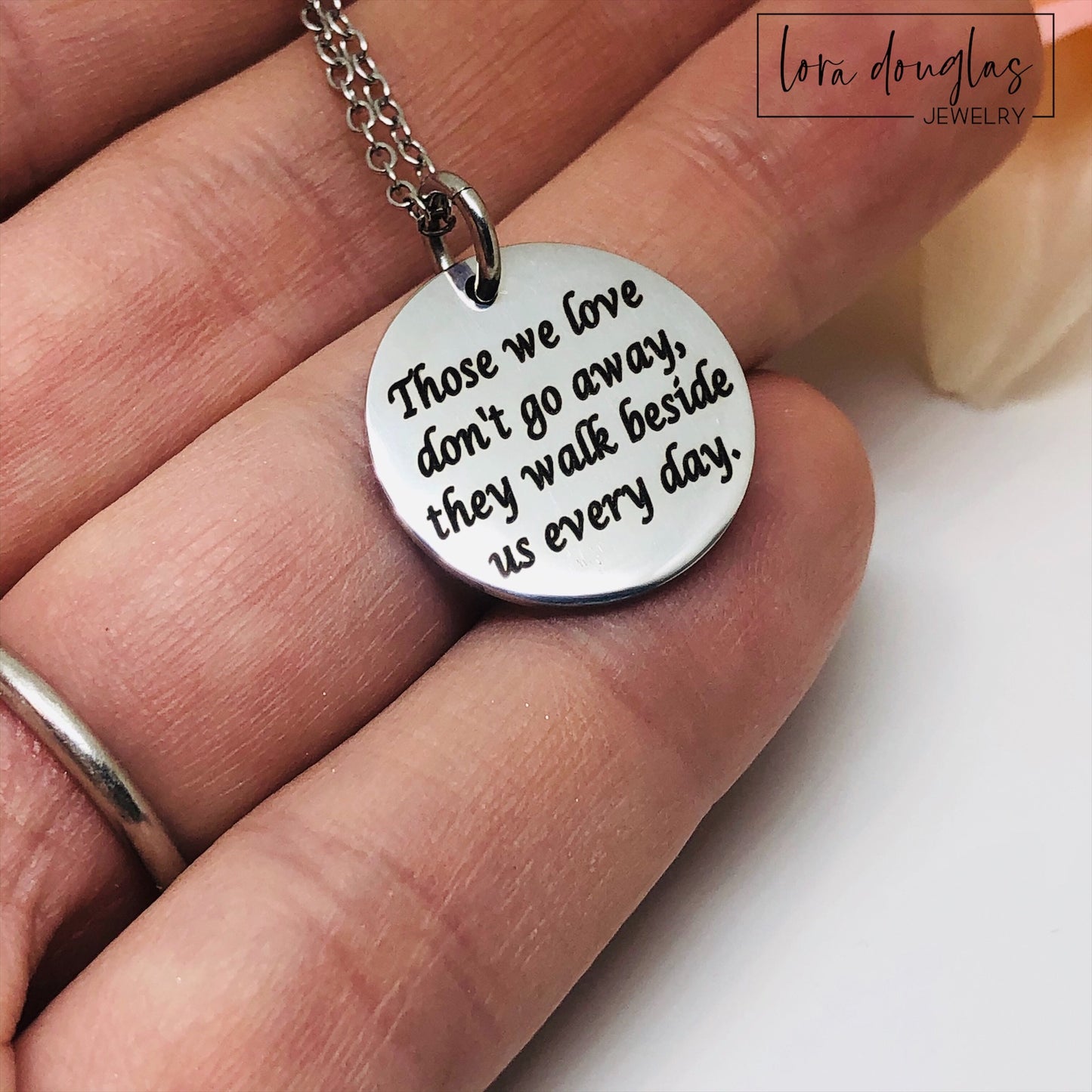 Silver necklace with a round pendant on a white background. Engraved with Those We Love Don't Go Away They Walk Beside Us Every Day.