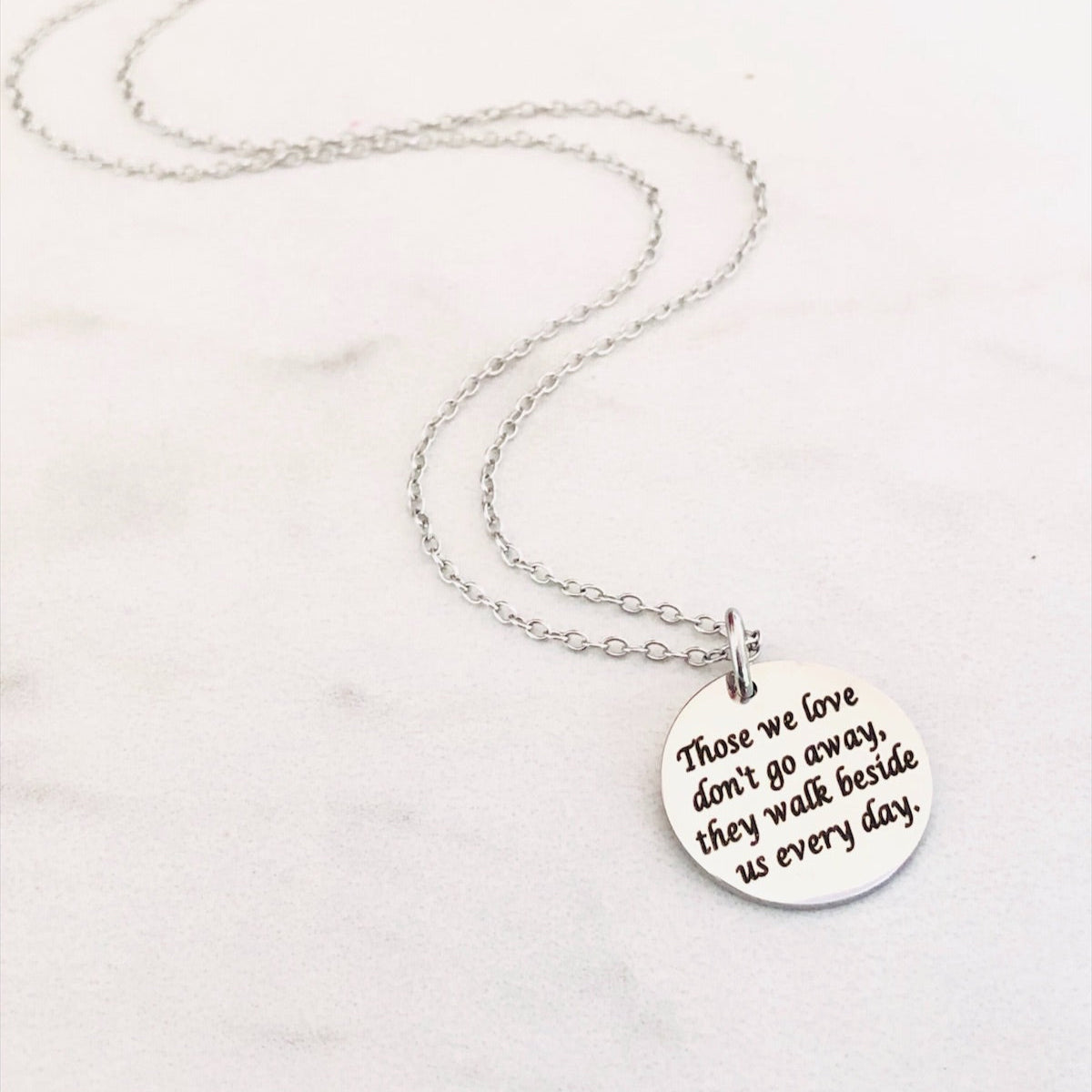 Silver necklace with a round pendant on a white background. Engraved with Those We Love Don't Go Away They Walk Beside Us Every Day.