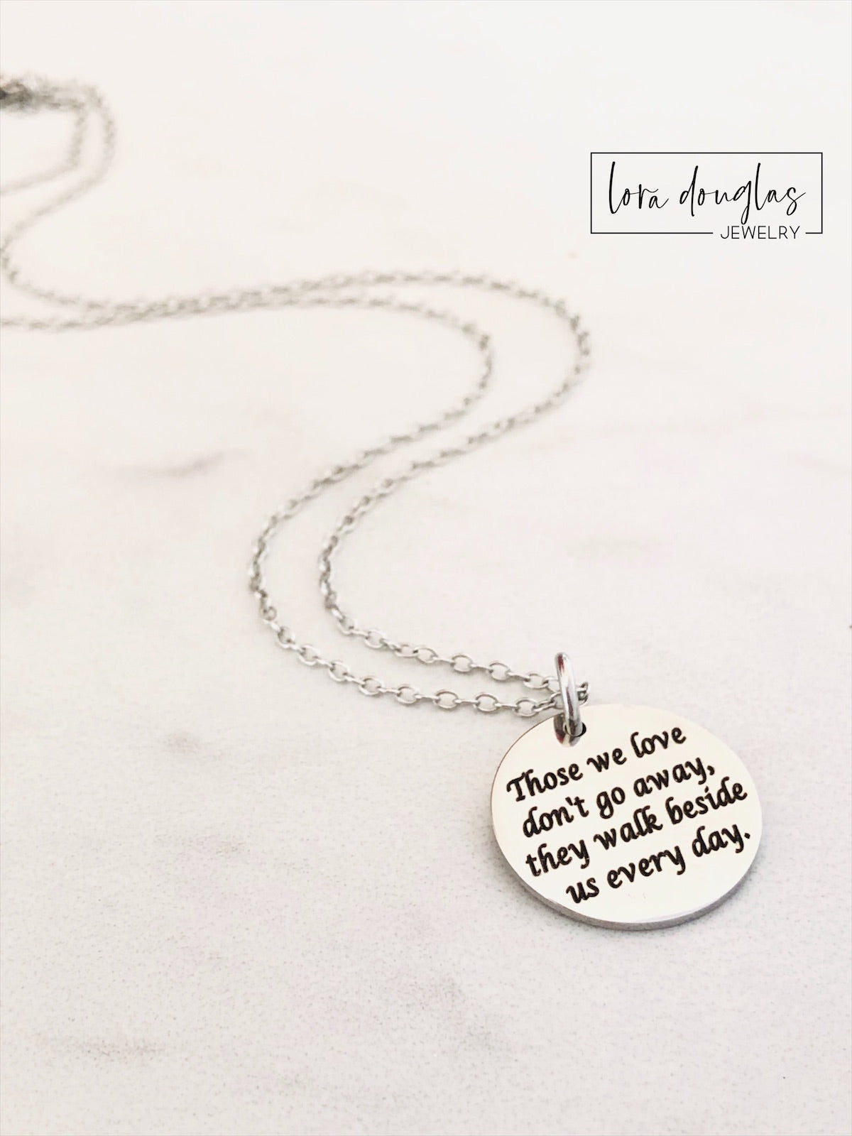 Silver necklace with a round pendant on a white background. Engraved with Those We Love Don't Go Away They Walk Beside Us Every Day.