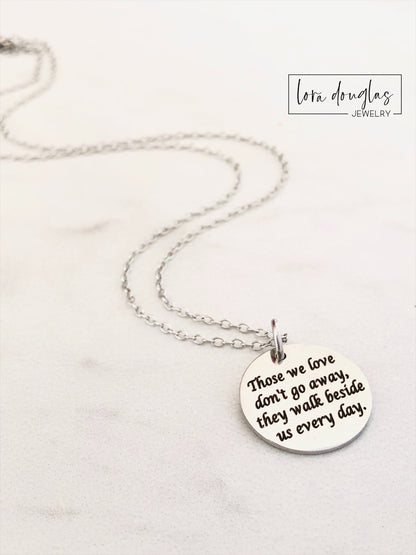 Silver necklace with a round pendant on a white background. Engraved with Those We Love Don't Go Away They Walk Beside Us Every Day.