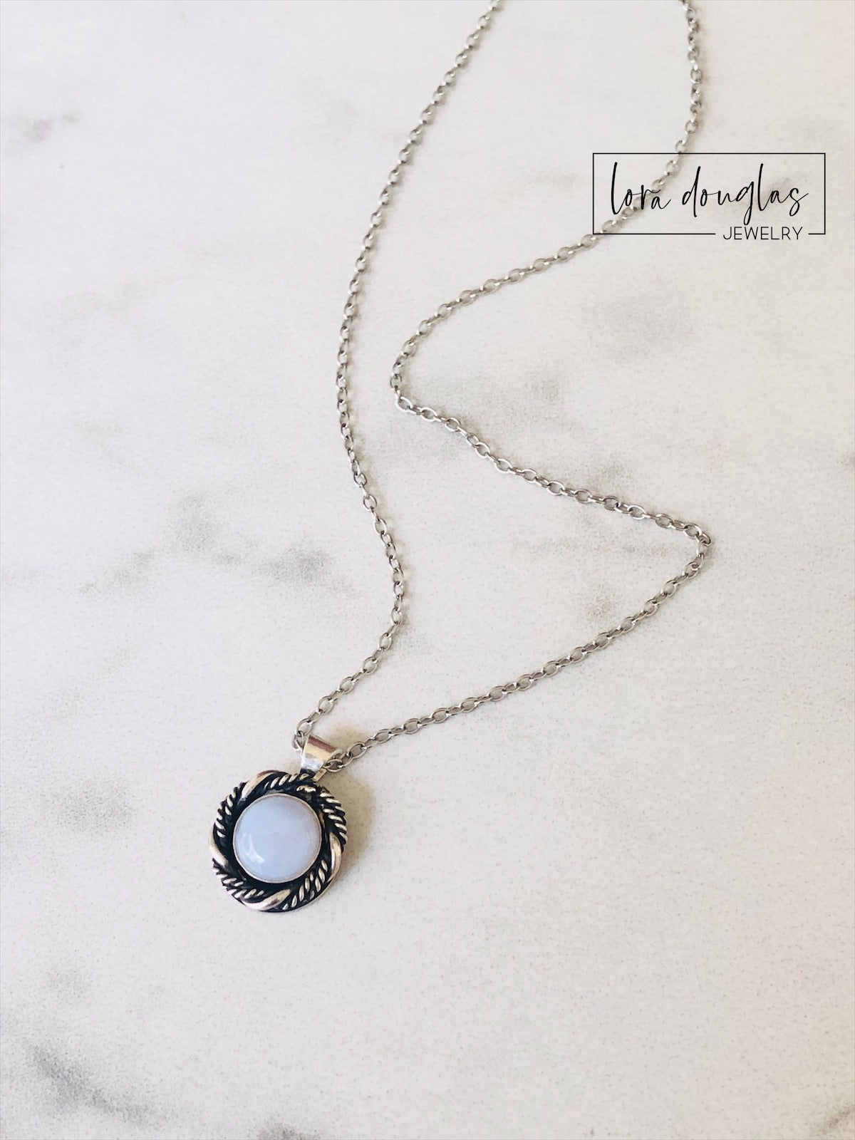 A sterling silver pendant necklace with a chalcedony stone set in a silver setting, attached to a sterling silver chain.