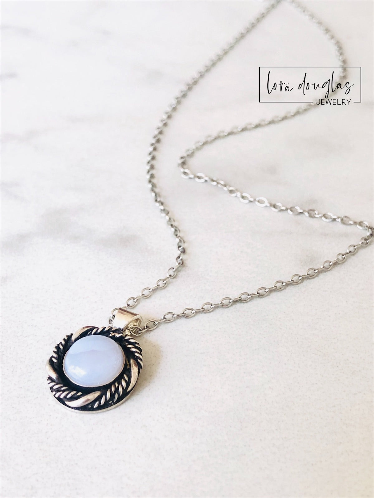 A sterling silver pendant necklace with a chalcedony stone set in a silver setting, attached to a sterling silver chain.