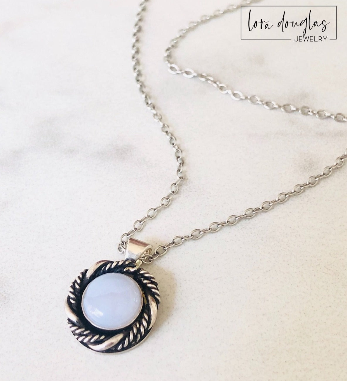 A sterling silver pendant necklace with a chalcedony stone set in a silver setting, attached to a sterling silver chain.