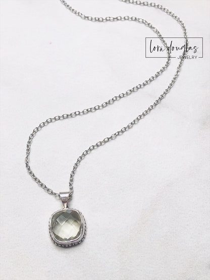 A sterling silver pendant necklace with a faceted green amethyst gemstone, attached to a silver chain.