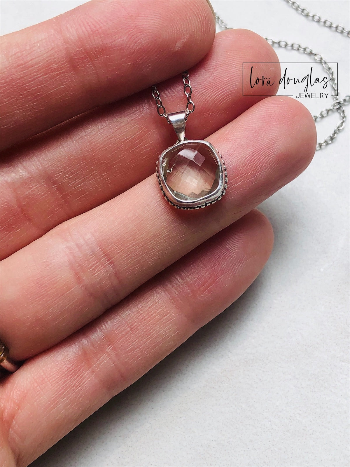 A sterling silver pendant necklace with a faceted green amethyst gemstone, attached to a silver chain.