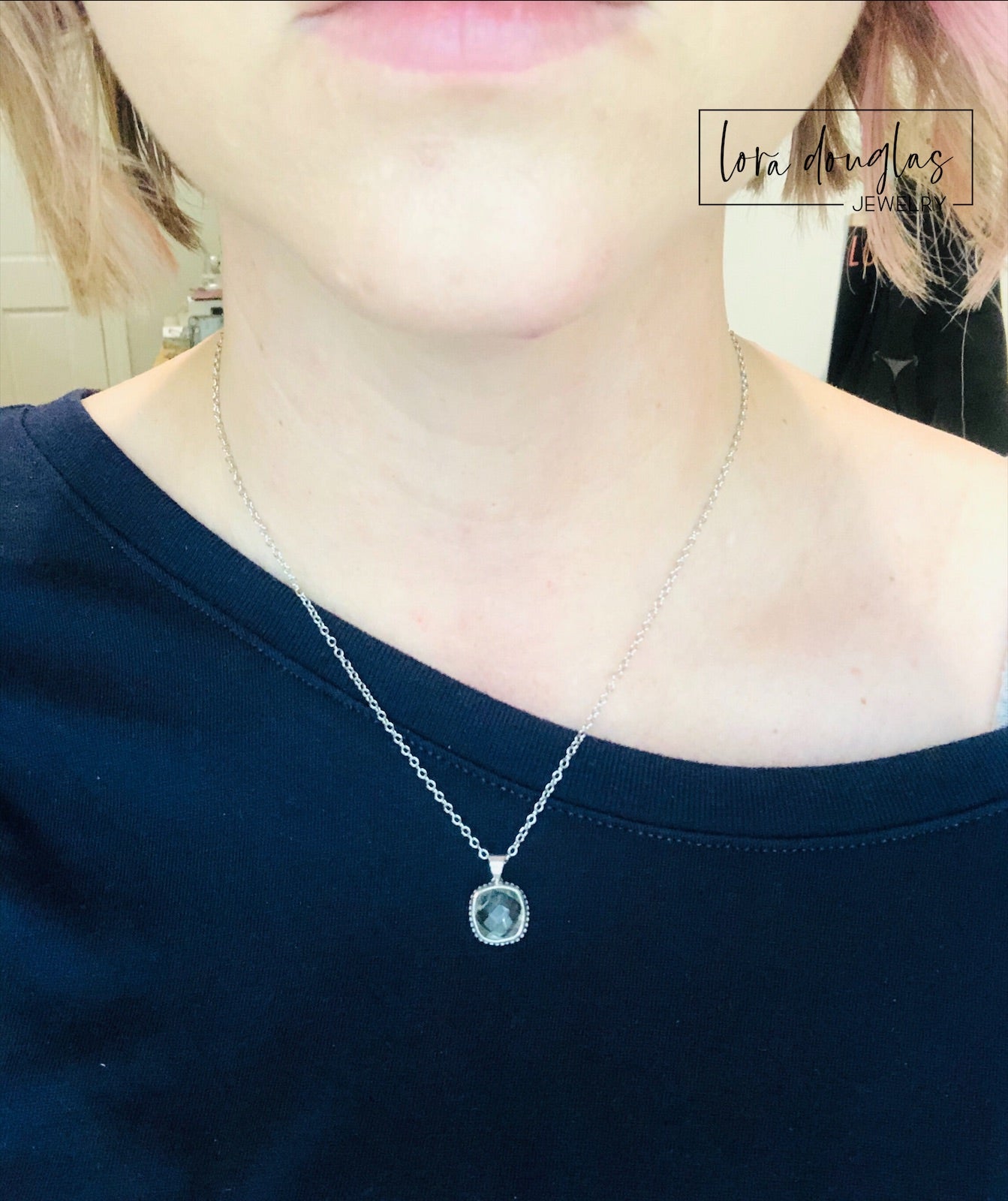 A sterling silver pendant necklace with a faceted green amethyst gemstone, attached to a silver chain.