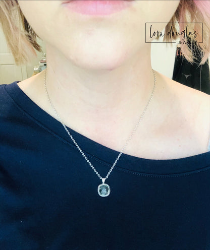 A sterling silver pendant necklace with a faceted green amethyst gemstone, attached to a silver chain.