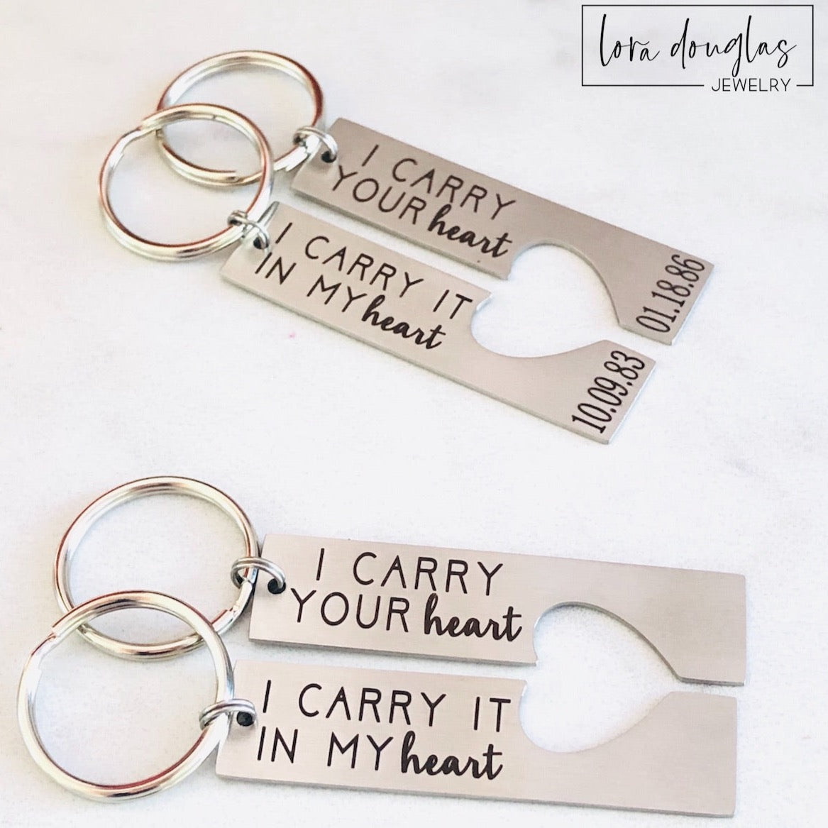 Two stainless steel key chains with laser engraved text 'I CARRY YOUR HEART' and 'I Carry it IN MY HEART' respectively, on a white background.