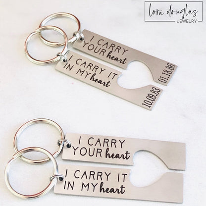 Two stainless steel key chains with laser engraved text 'I CARRY YOUR HEART' and 'I Carry it IN MY HEART' respectively, on a white background.