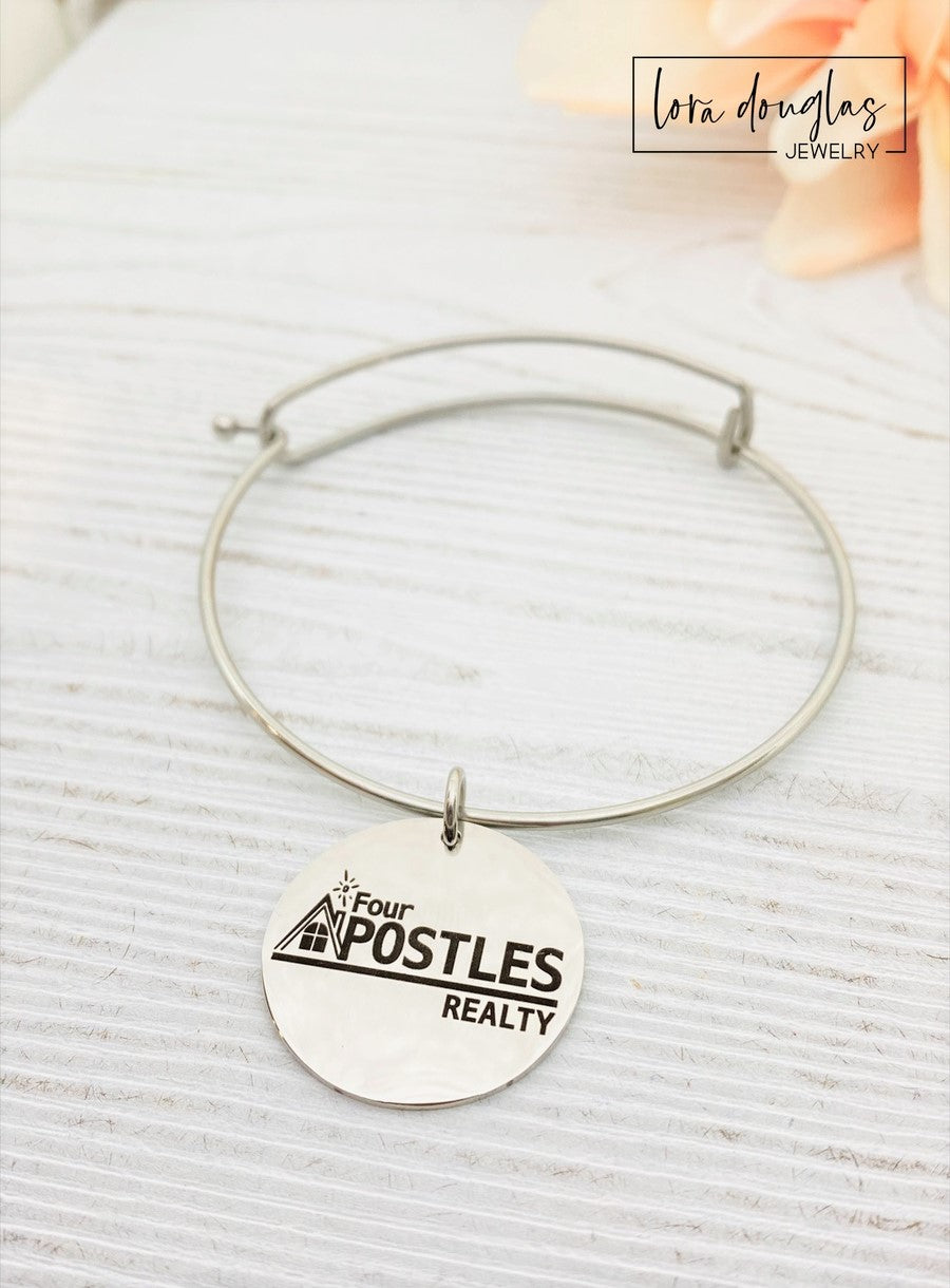 Three custom jewelry charms with engraved logos on a disc-shaped pendant, attached to different types of jewelry including a necklace and a bracelet, with the option to engrave your logo.