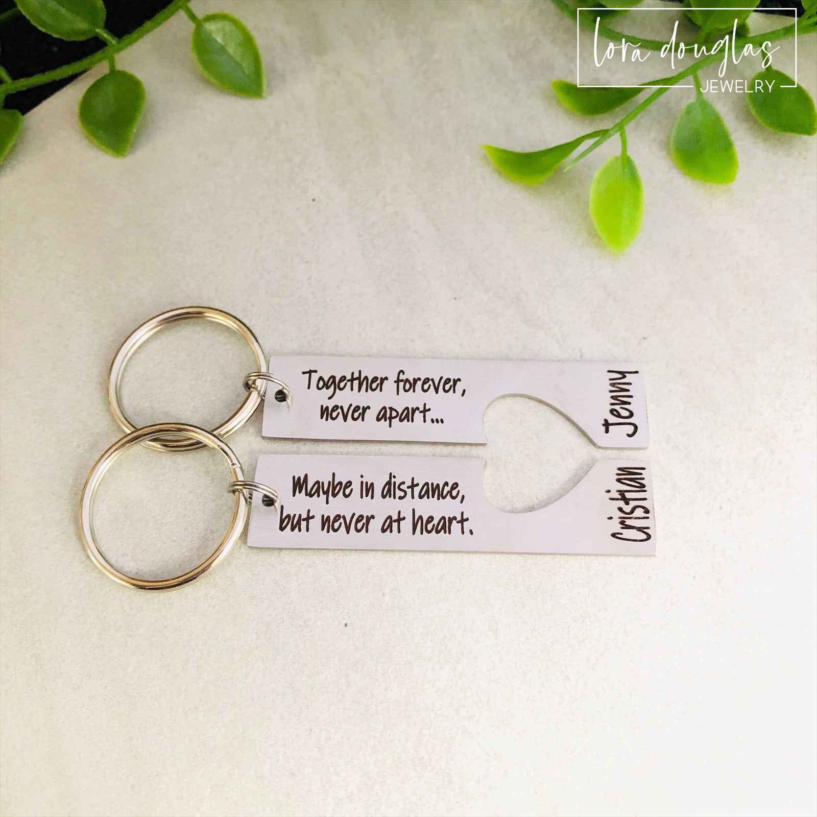 A stainless steel heart-shaped keychain with engraved text 'Together Forever Never Apart Maybe in Distance but Never at Heart' The keychain is silver-colored and has a personalized engraving.