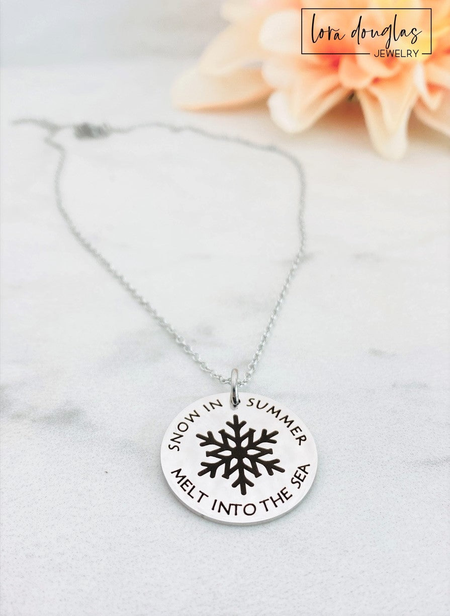 A collection of personalized jewelry items including necklaces, bracelets, and charms with engraved text and simple graphics on circular discs.