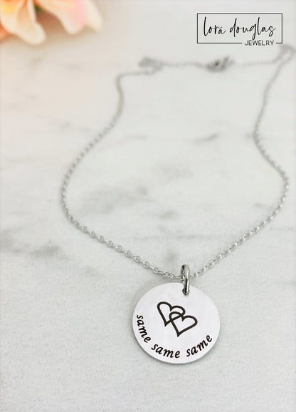 A collection of personalized jewelry items including necklaces, bracelets, and charms with engraved text and simple graphics on circular discs.
