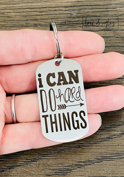 stainless steel keychains with the engraved text 'I CAN DO HARD THINGS' on a black background.
