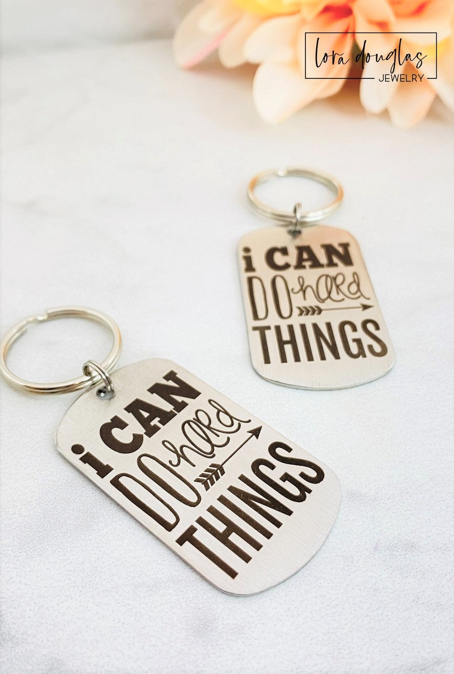stainless steel keychains with the engraved text 'I CAN DO HARD THINGS' on a black background.