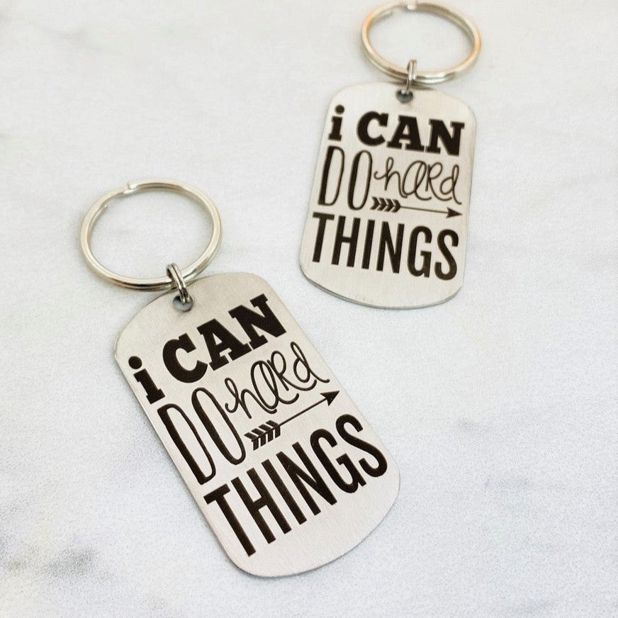 stainless steel keychains with the engraved text 'I CAN DO HARD THINGS' on a black background.