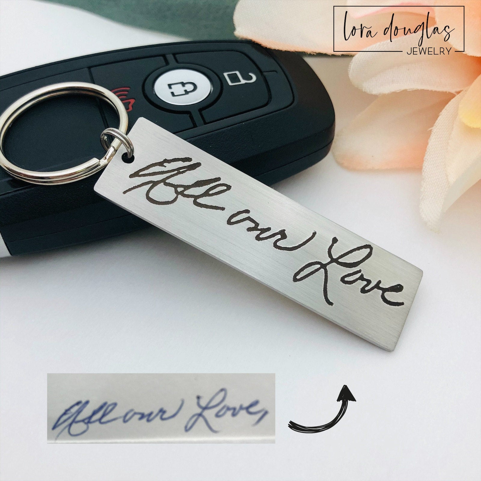 A stainless steel keychain with engraved handwriting samples. The keychain features a silver-colored plate with the text 'I love you dad' and 'Mom you're the best' alongside a standard key ring.
