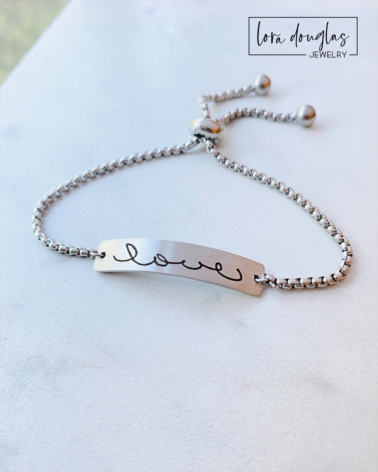 Adjustable stainless steel bracelet engraved with a handwritten message.