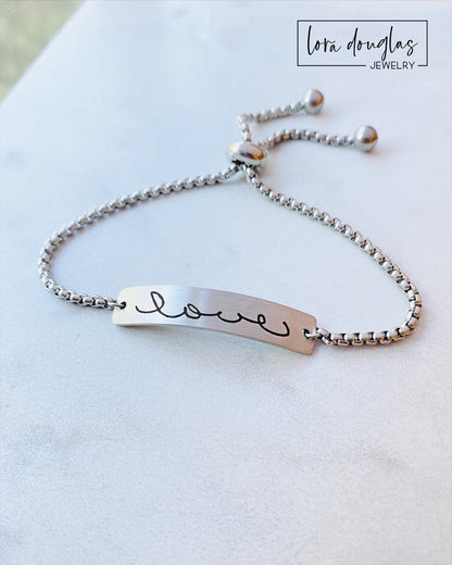 Adjustable stainless steel bracelet engraved with a handwritten message.