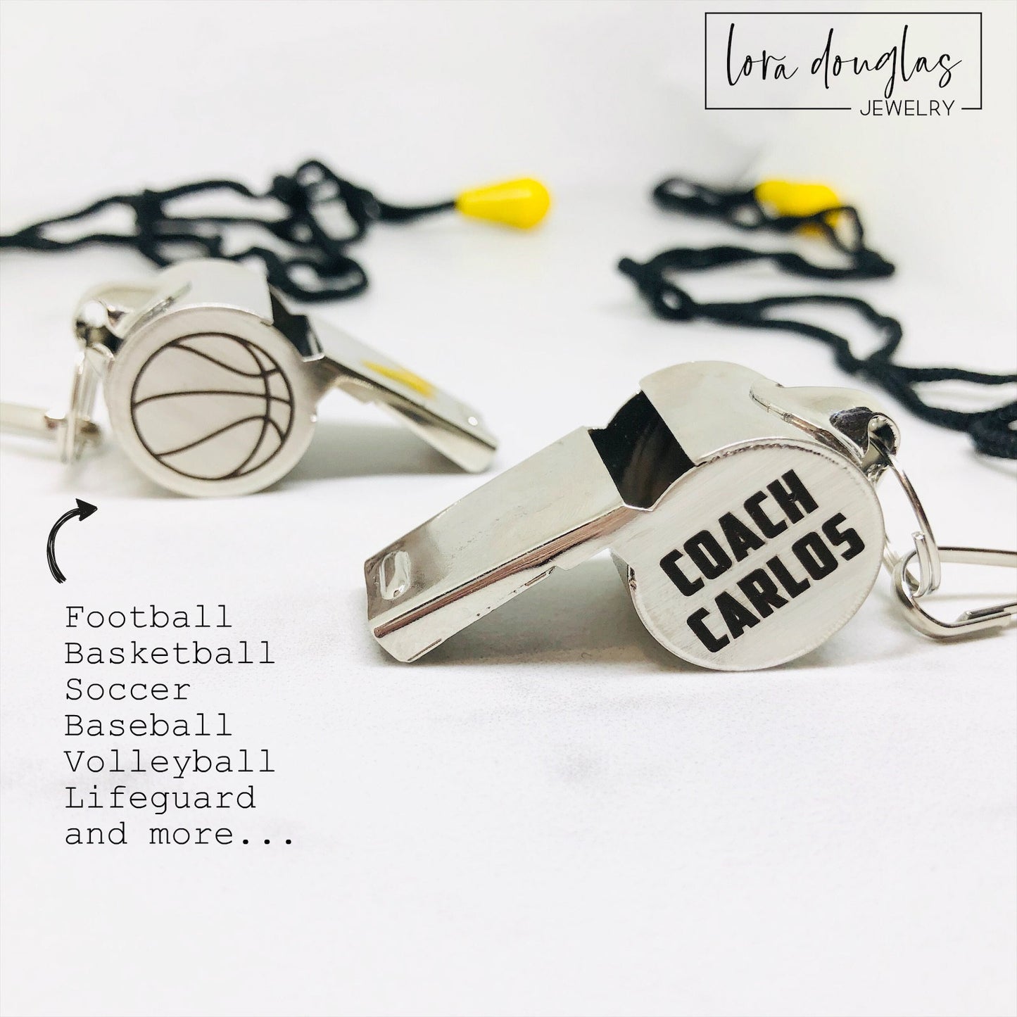 personalized stainless steel whistles with engraved text, one with 'COACH CARLOS' and sports icons, the other with 'FOOTBALL BASKETBALL SOCCER LIFEGUARD AND MORE'. Both whistles have a lanyard 