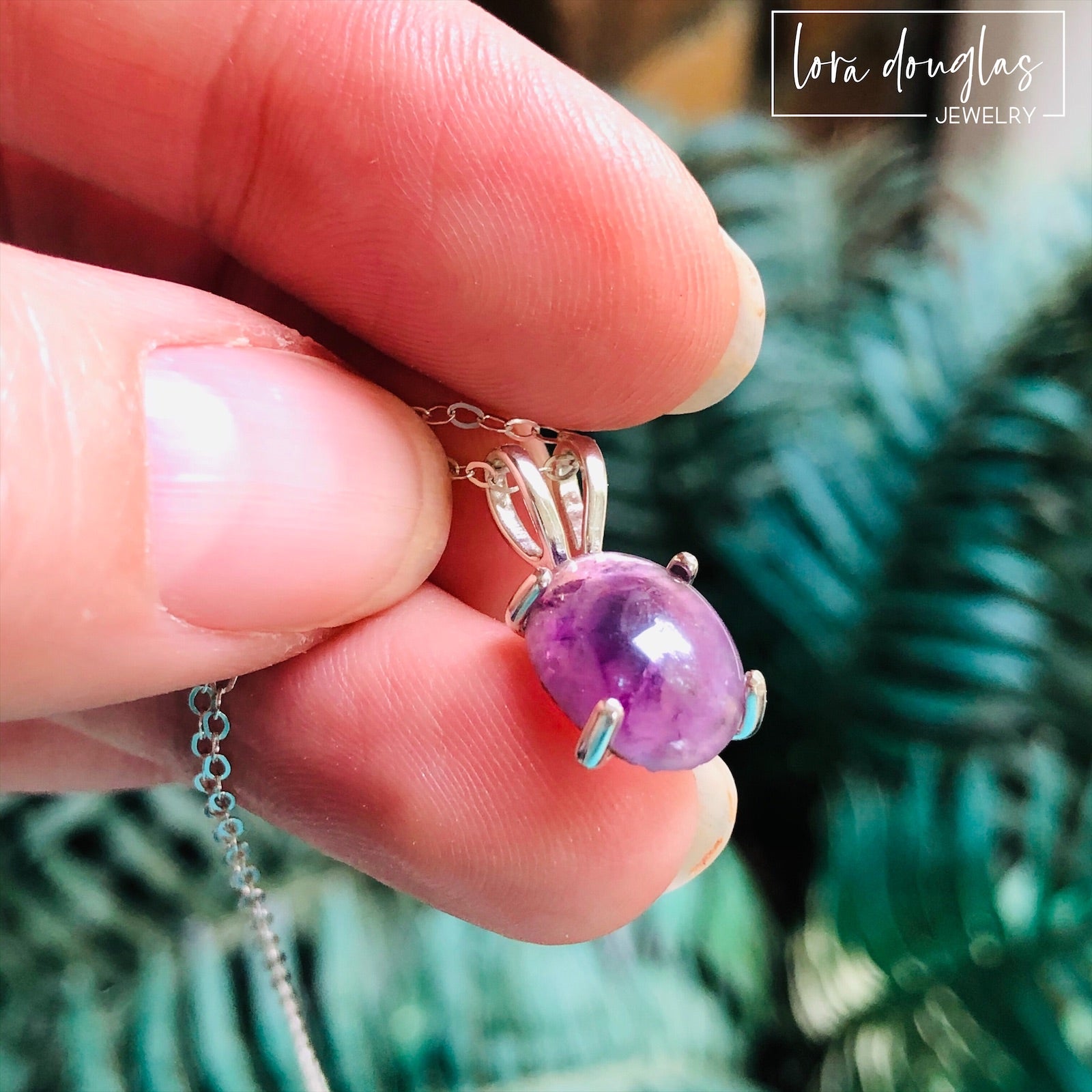 A sterling silver pendant necklace with a hand-cut amethyst gemstone, displayed on a silver chain against a black background.