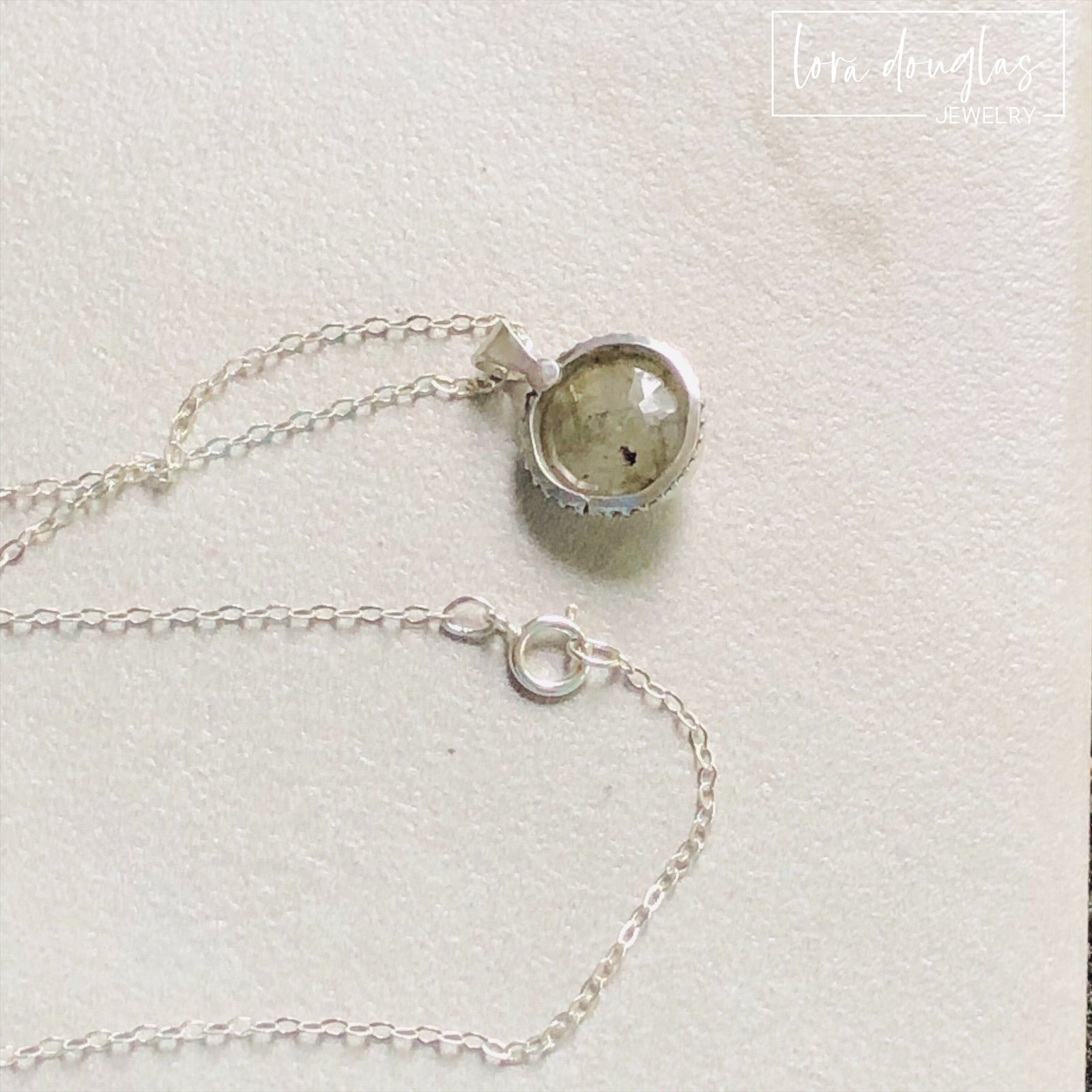 A sterling silver pendant necklace with a faceted labradorite gemstone in the center, attached to an 18-inch chain with a C clasp.