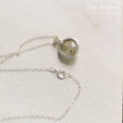 A sterling silver pendant necklace with a faceted labradorite gemstone in the center, attached to an 18-inch chain with a C clasp.
