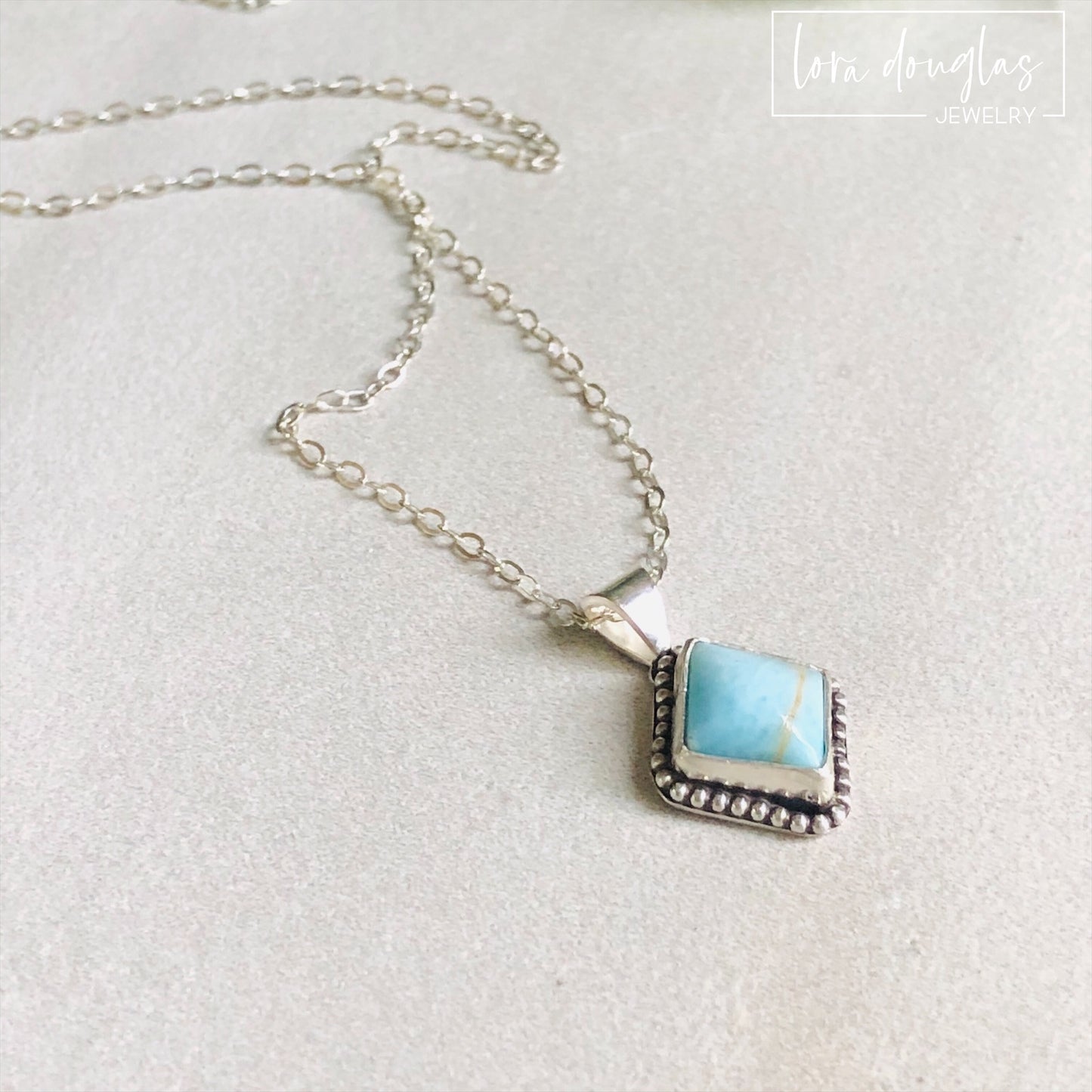 A sterling silver pendant necklace with a turquoise stone and a silver chain.