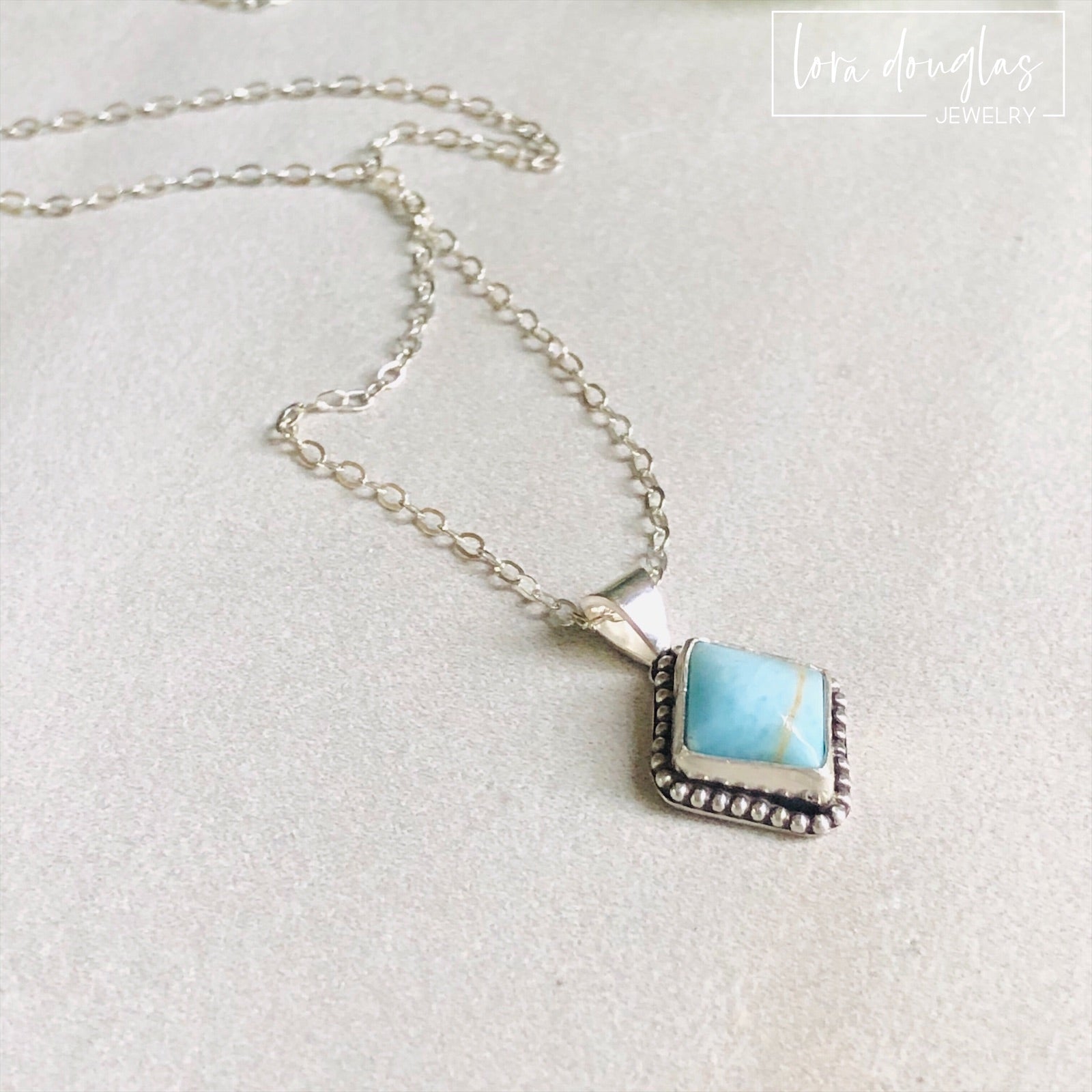 A sterling silver pendant necklace with a turquoise stone and a silver chain.
