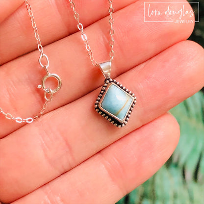 A sterling silver pendant necklace with a turquoise stone and a silver chain.