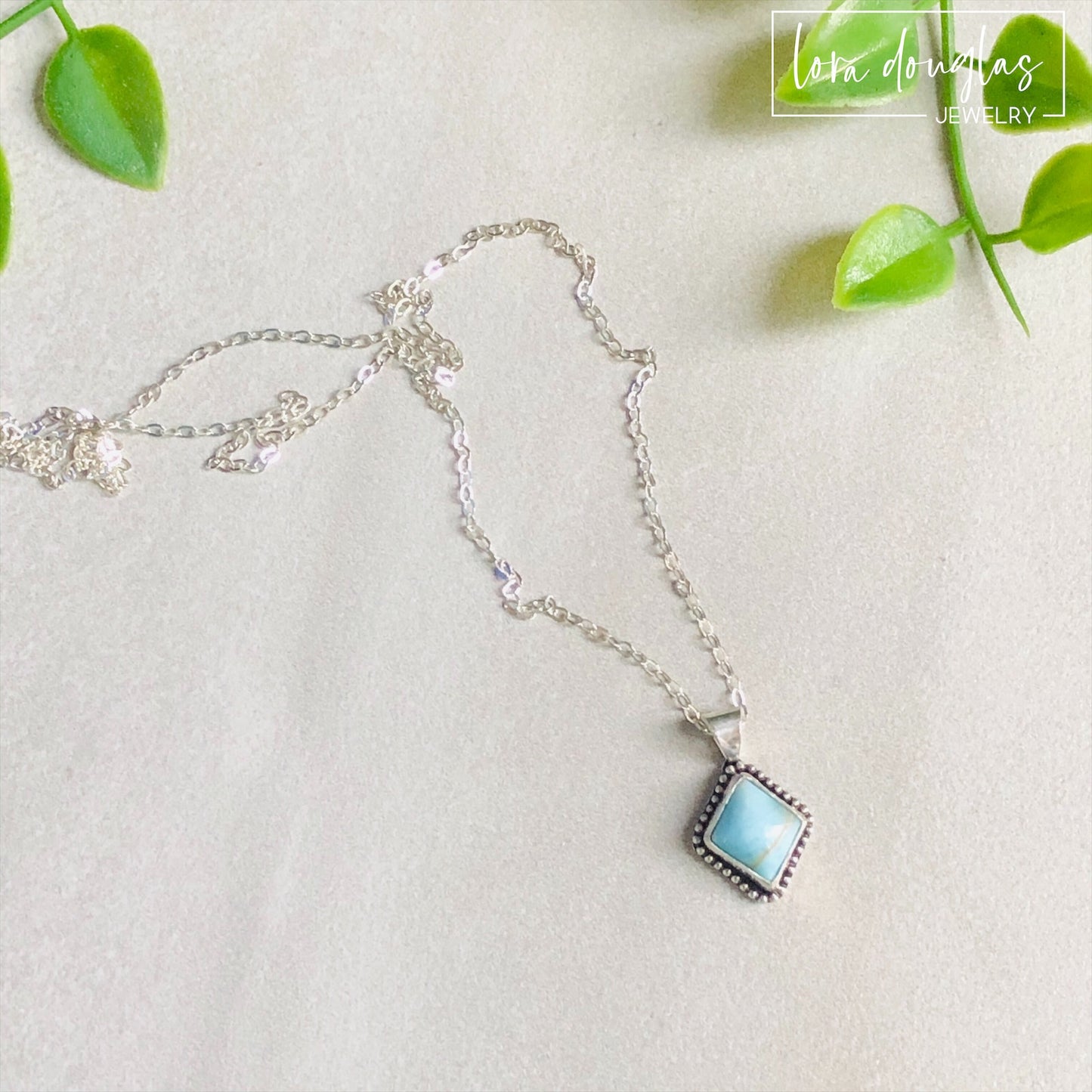 A sterling silver pendant necklace with a turquoise stone and a silver chain.
