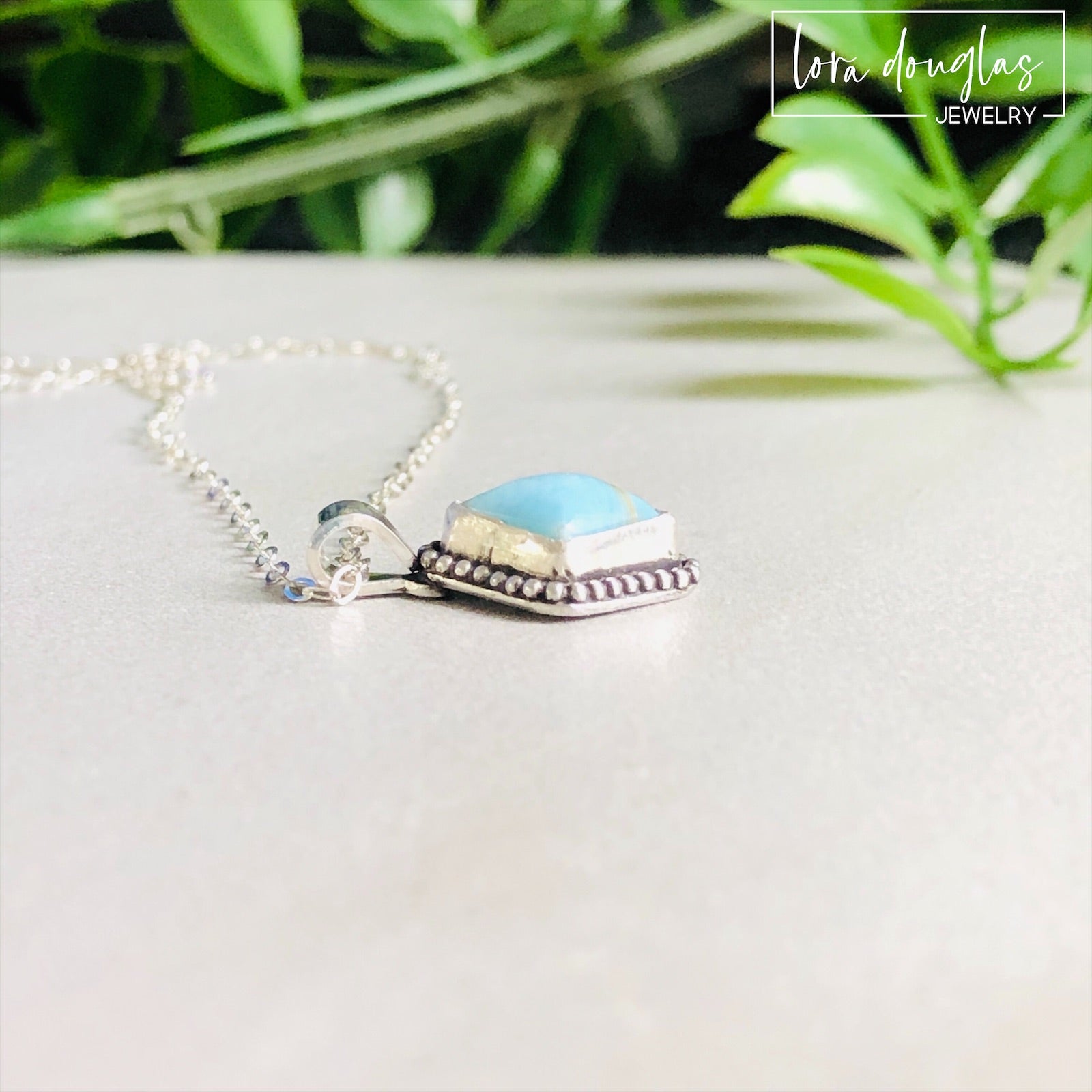 A sterling silver pendant necklace with a turquoise stone and a silver chain.