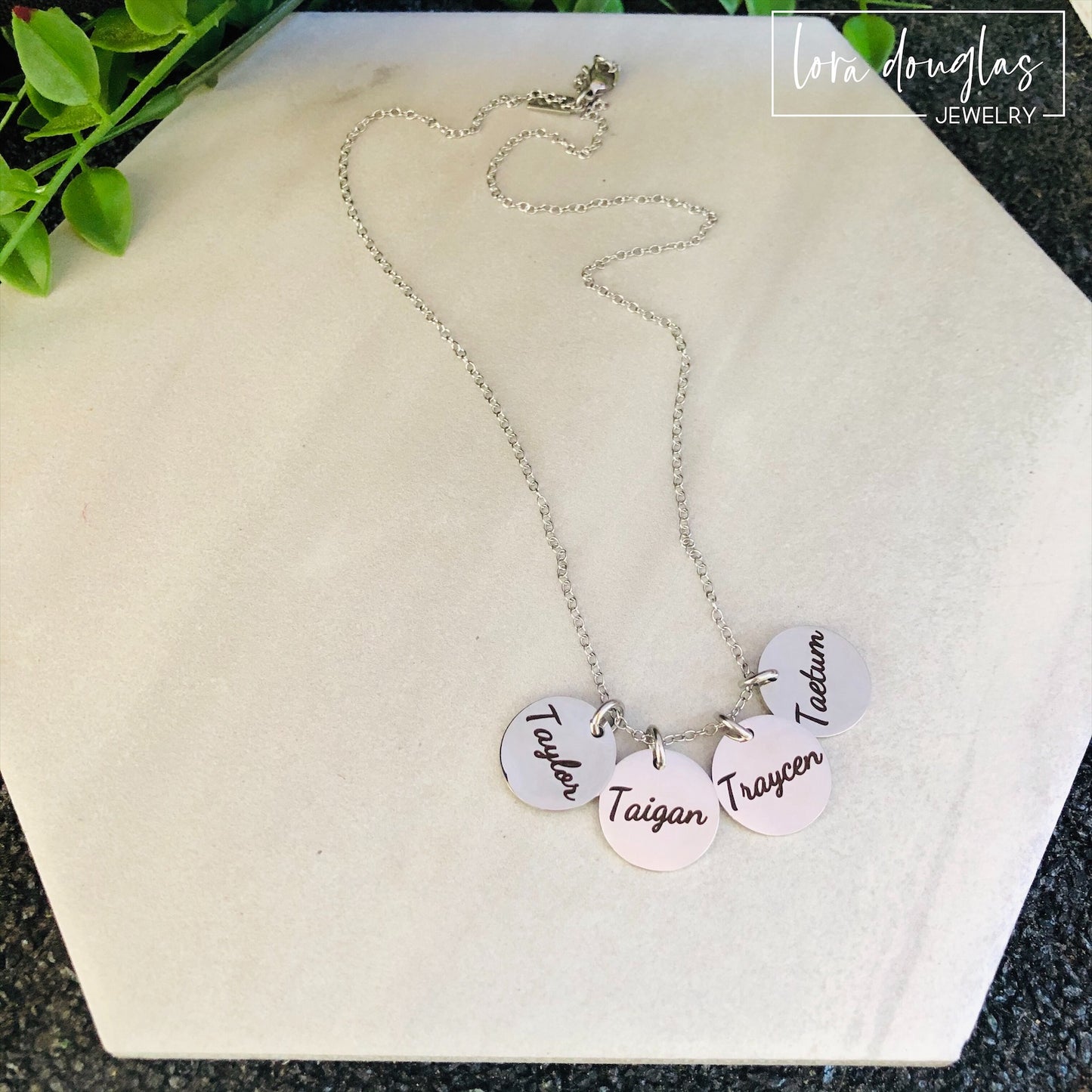 silver disc necklace with four round discs engraved with names