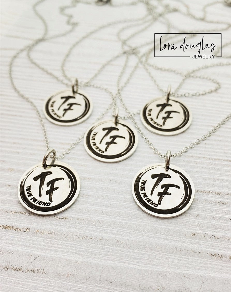 Three custom jewelry charms with engraved logos on a disc-shaped pendant, attached to different types of jewelry including a necklace and a bracelet, with the option to engrave your logo.