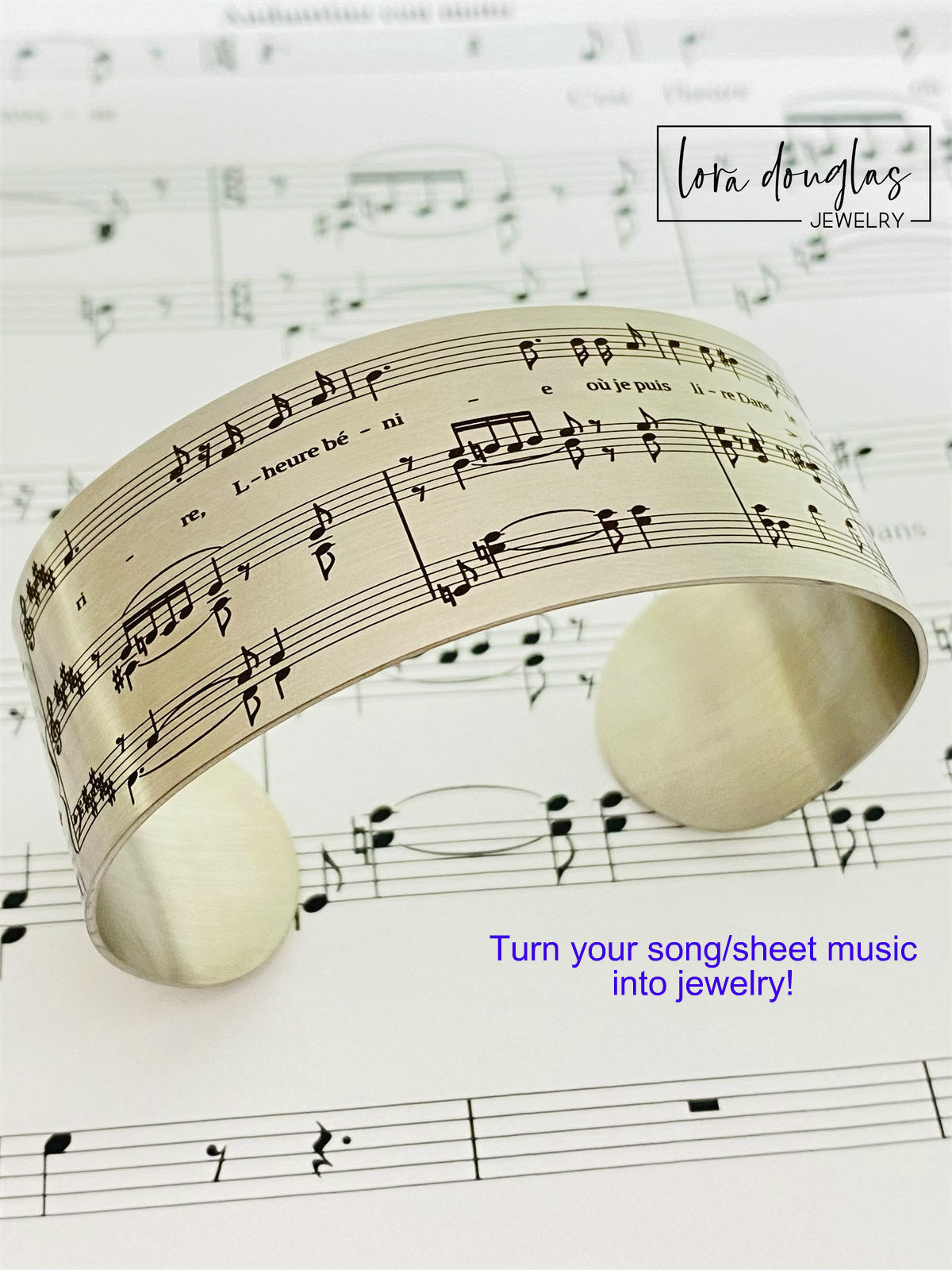 A stainless steel bracelet with sheet music engraving, displayed on a background of sheet music.