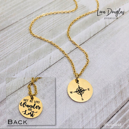Gold  stainless steel compass jewelry with a round pendant that reads 'Not all who wander are lost' on a chain.