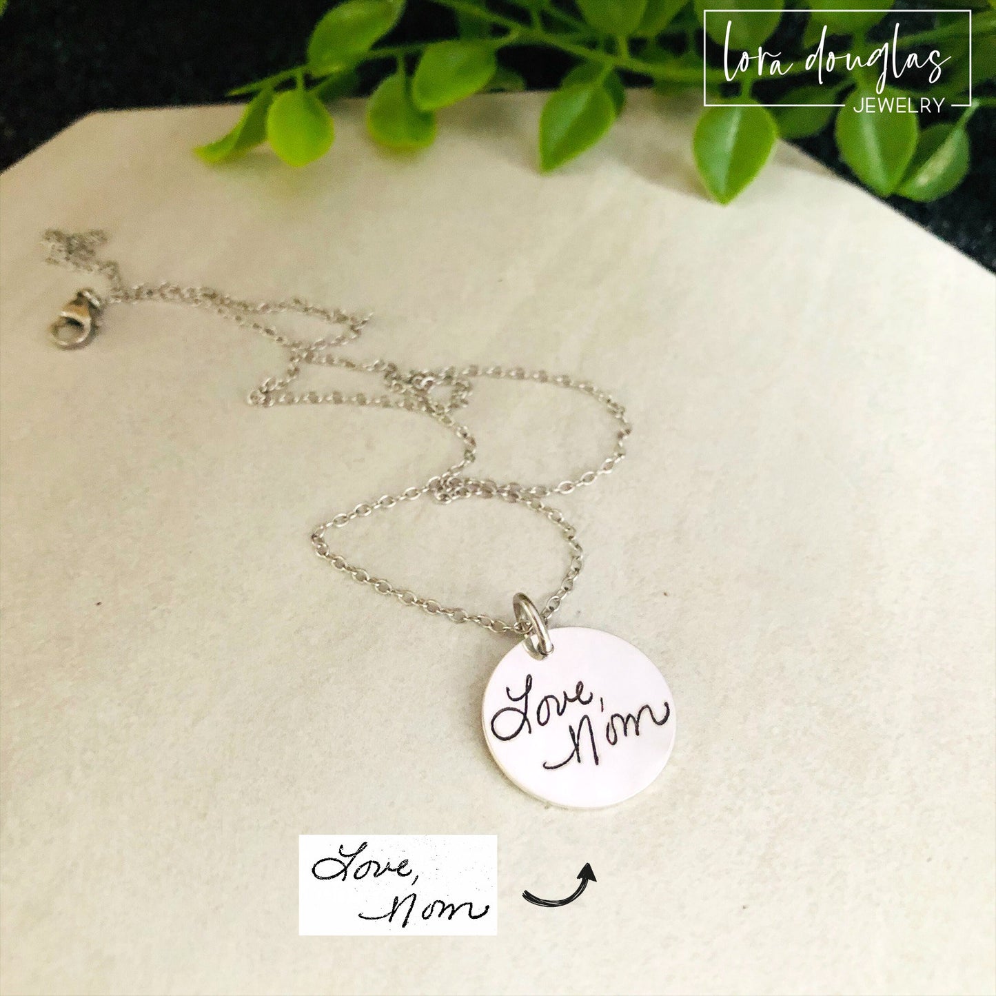 A round silver pendant with engraved with handwritten text 