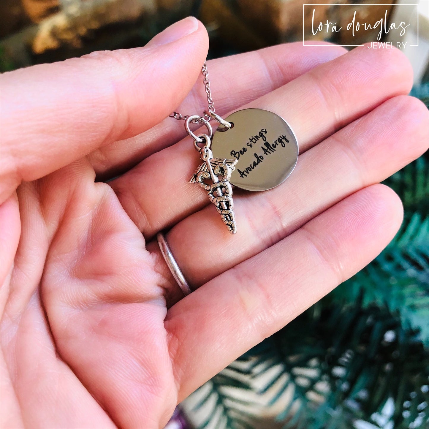 A stainless steel medical alert necklace with a round pendant displaying medical information and a 24-inch chain.