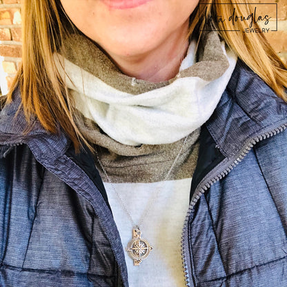 A silver compass necklace with a stainless steel pendant with personalized latitude and longitude coordinates