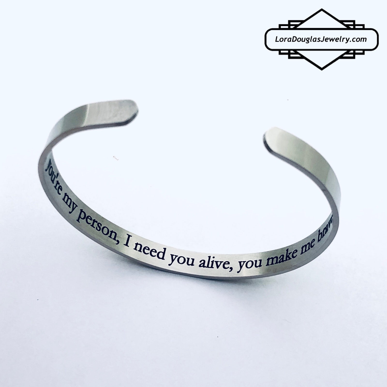 A stainless steel cuff bracelet with a secret message engraved on the inside, against the skin. The bracelet is blank on the outside.